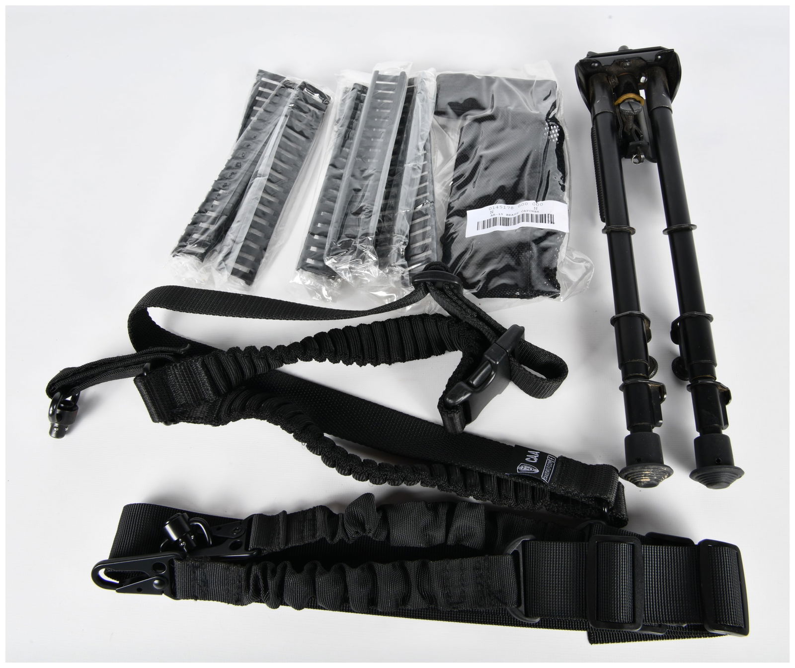 A Collection of Tactical Firearm Accessories, including an Adjustable Bipod, CAA Sling, and AR-15: This lot comprises a collection of contemporary tactical firearm accessories. It includes a black-finished metal bipod with adjustable legs, consistent with a common Harris-style design. Also present