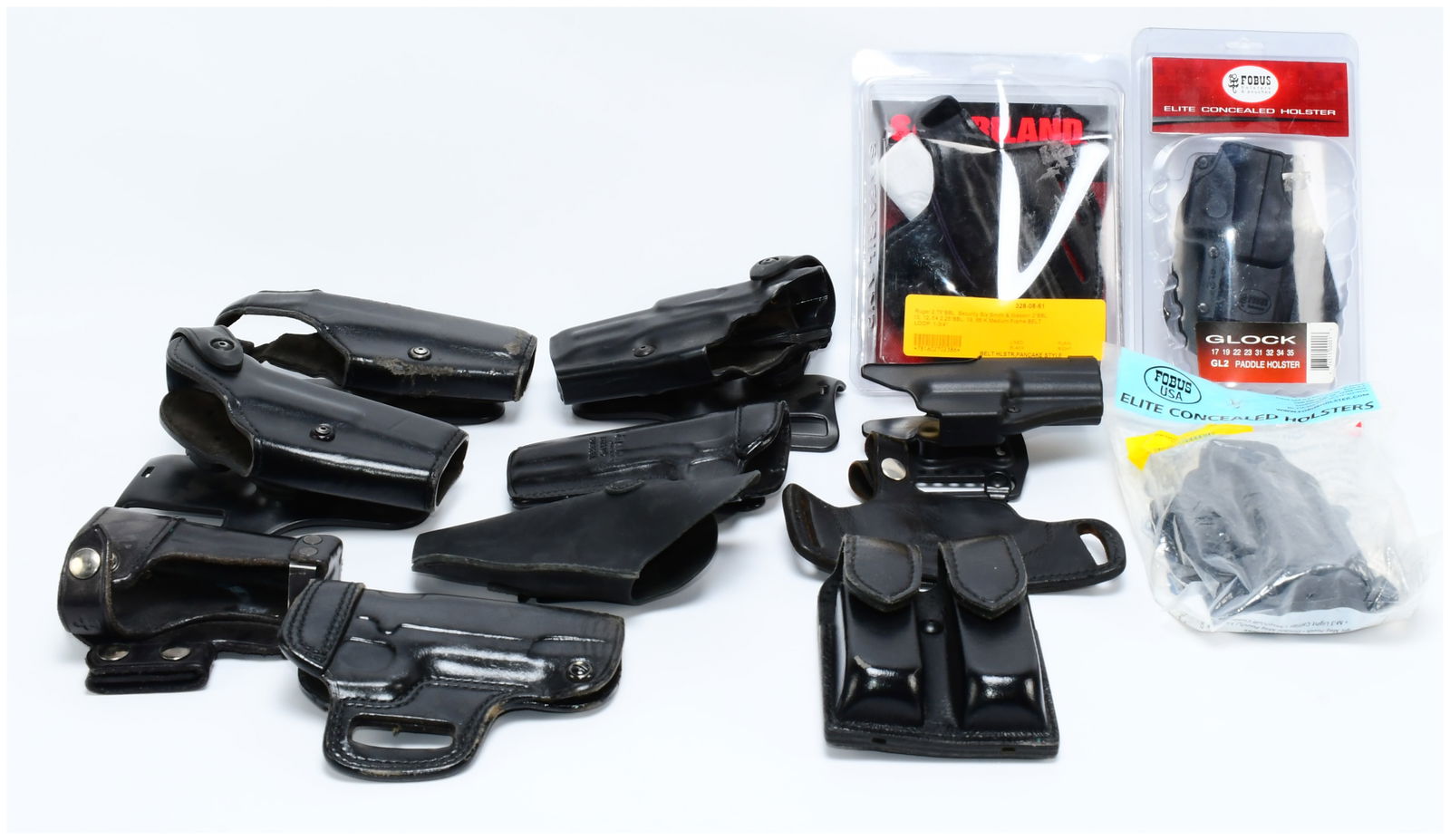 A Collection of Modern Firearm Holsters and Magazine Pouch, including Safariland, FOBUS, and Bianchi: A collection of modern firearm holsters and one double magazine pouch, primarily constructed from black molded polymer and black leather. The lot includes several items new in sealed retail packaging,