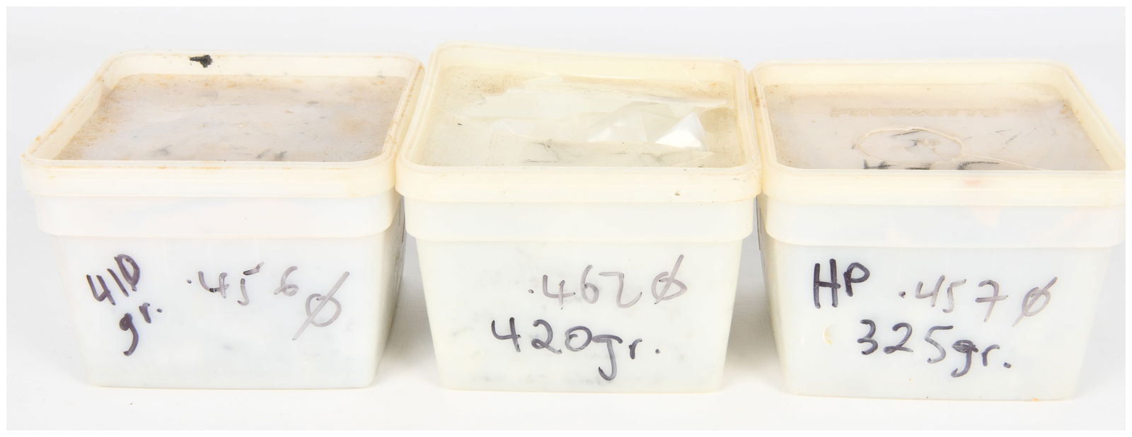 Three Containers of Cast Lead Bullets, including .45-60, .462, and .45-70 Calibers: A group of three opaque off-white rectangular plastic containers, each with a lid, holding numerous unjacketed lead or lead alloy projectiles. The containers, which appear to be repurposed general sto
