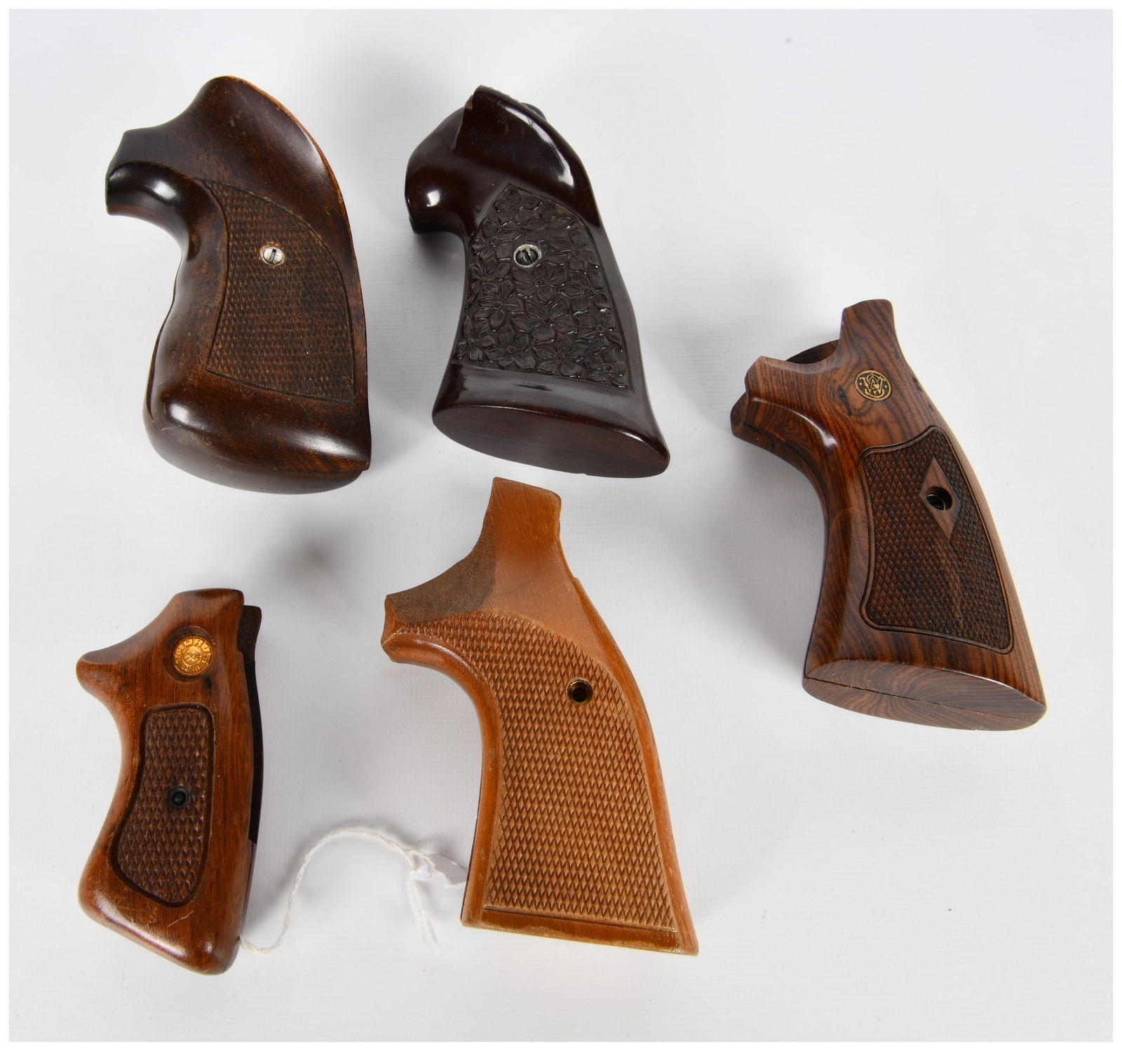 A Collection of Five Assorted Wood Handgun Grips, including Smith & Wesson and Taurus: A collection of five assorted handgun grip panels, primarily crafted from various shades of polished wood. This group includes examples for Smith & Wesson and Taurus firearms, with other grips likely