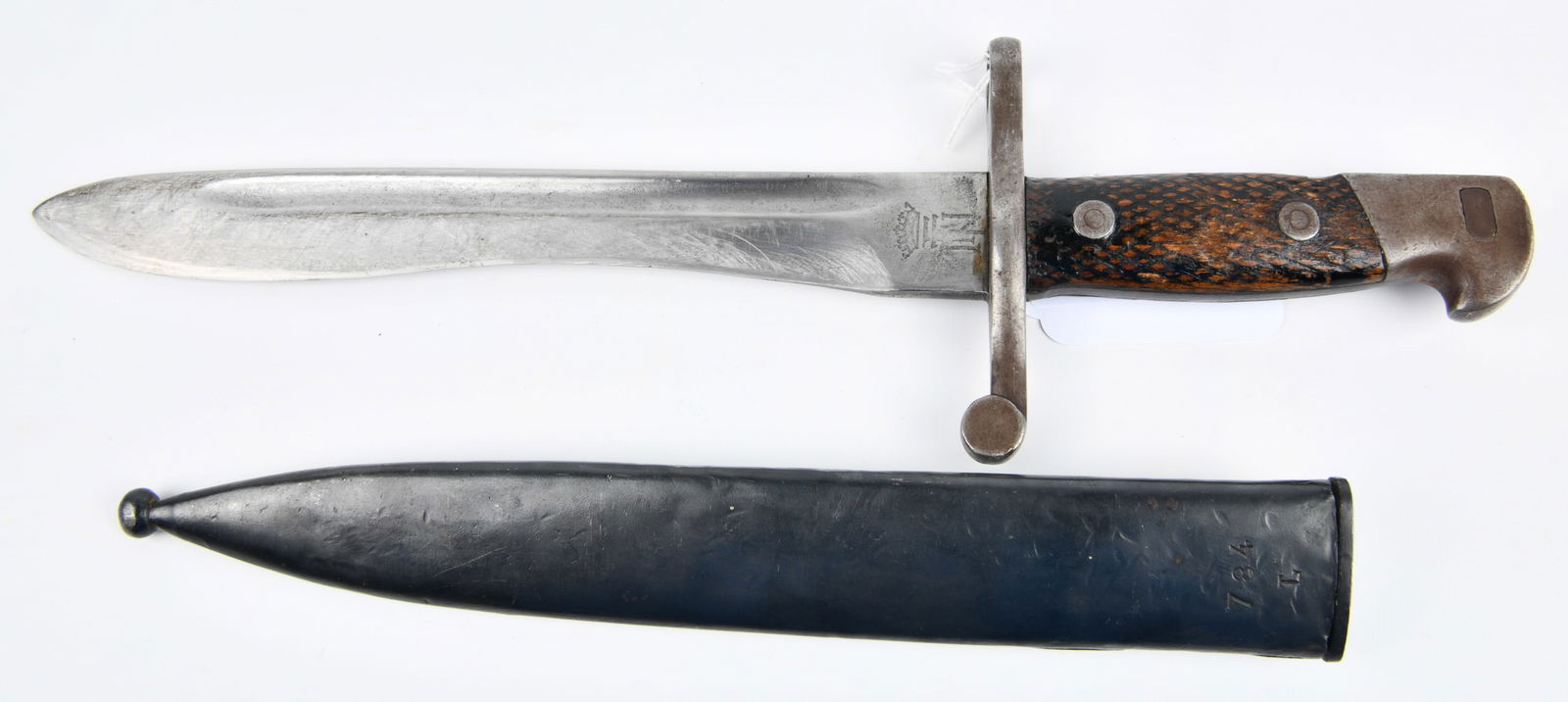 Spanish M1941 Bolo Bayonet with Scabbard: A Spanish M1941 Bolo Bayonet with Scabbard. This military bayonet features a fullered steel blade of distinctive bolo form, paired with a dark-finished metal scabbard. The bayonet is constructed with