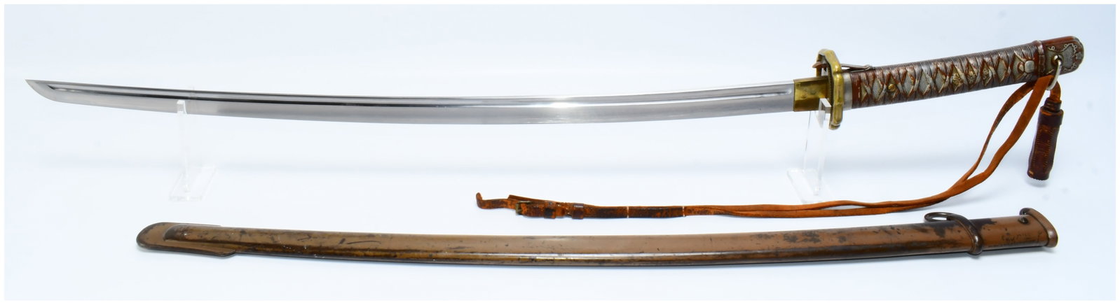 A WWII Japanese Army Officer's Type 98 Shin-Gunto Katana Sword: This is a Japanese Army Officer's Type 98 Shin-Gunto katana sword from the mid-20th century, presented with its scabbard and an attached leather strap. The sword features a polished steel blade, a bro