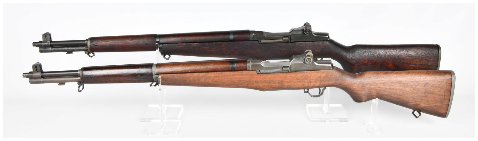 A Sequential Set of Two Beretta M1 Garand Pattern Semi-Automatic Rifles: This sequential set comprises two Beretta M1 Garand pattern semi-automatic military-style rifles. Both rifles feature wooden stocks, one of a lighter shade and the other darker, complemented by dark f