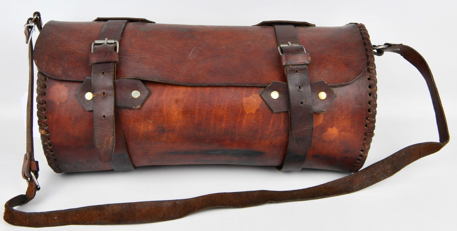 A Vintage Brown Leather Motorcycle Tool Roll Bag: A cylindrical dark brown leather bag, likely a tool roll or motorcycle bag, featuring a main compartment with a front flap closure. The flap is secured by two adjustable buckled straps with silver-ton