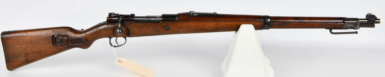 German Mauser Kar. 98 Bolt Action Carbine, Amberg 1910: A German Mauser Kar. 98 bolt-action military carbine, manufactured at the Amberg arsenal in 1910. The rifle is primarily constructed of blued steel and features a wooden stock, accompanied by a brown