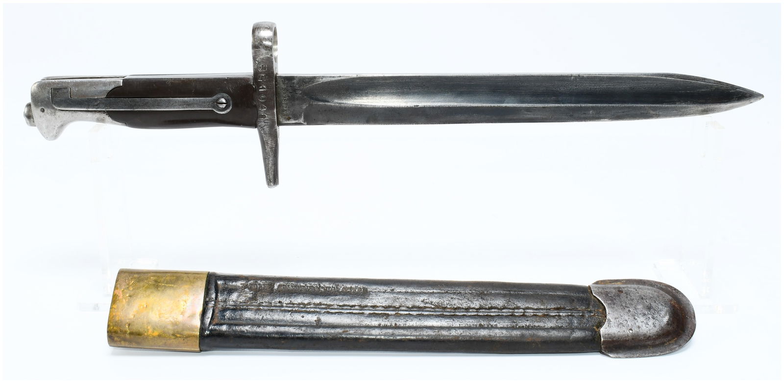 An Italian WW1 Shortened Bayonet & Scabbard: An Italian WW1 Shortened Bayonet and its accompanying scabbard, manufactured in Brescia. The bayonet features a single-edged, fullered steel blade, a steel hilt with a crossguard incorporating a muzzl
