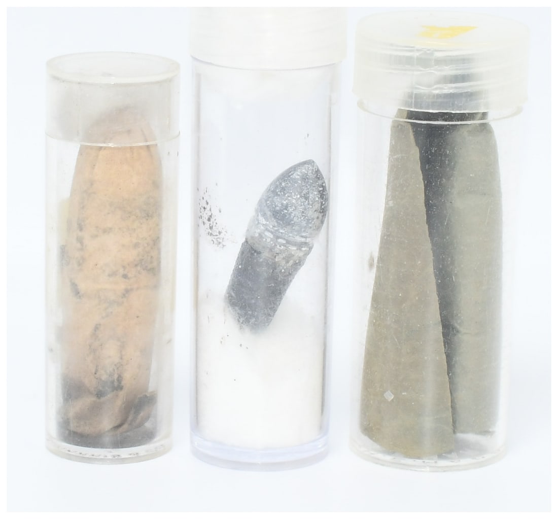 A Group of Mid-19th Century Ammunition Components: This group comprises historical ammunition components, consistent with mid-19th century firearms technology. It features several conical lead projectiles, commonly identified as Minie balls, which exh