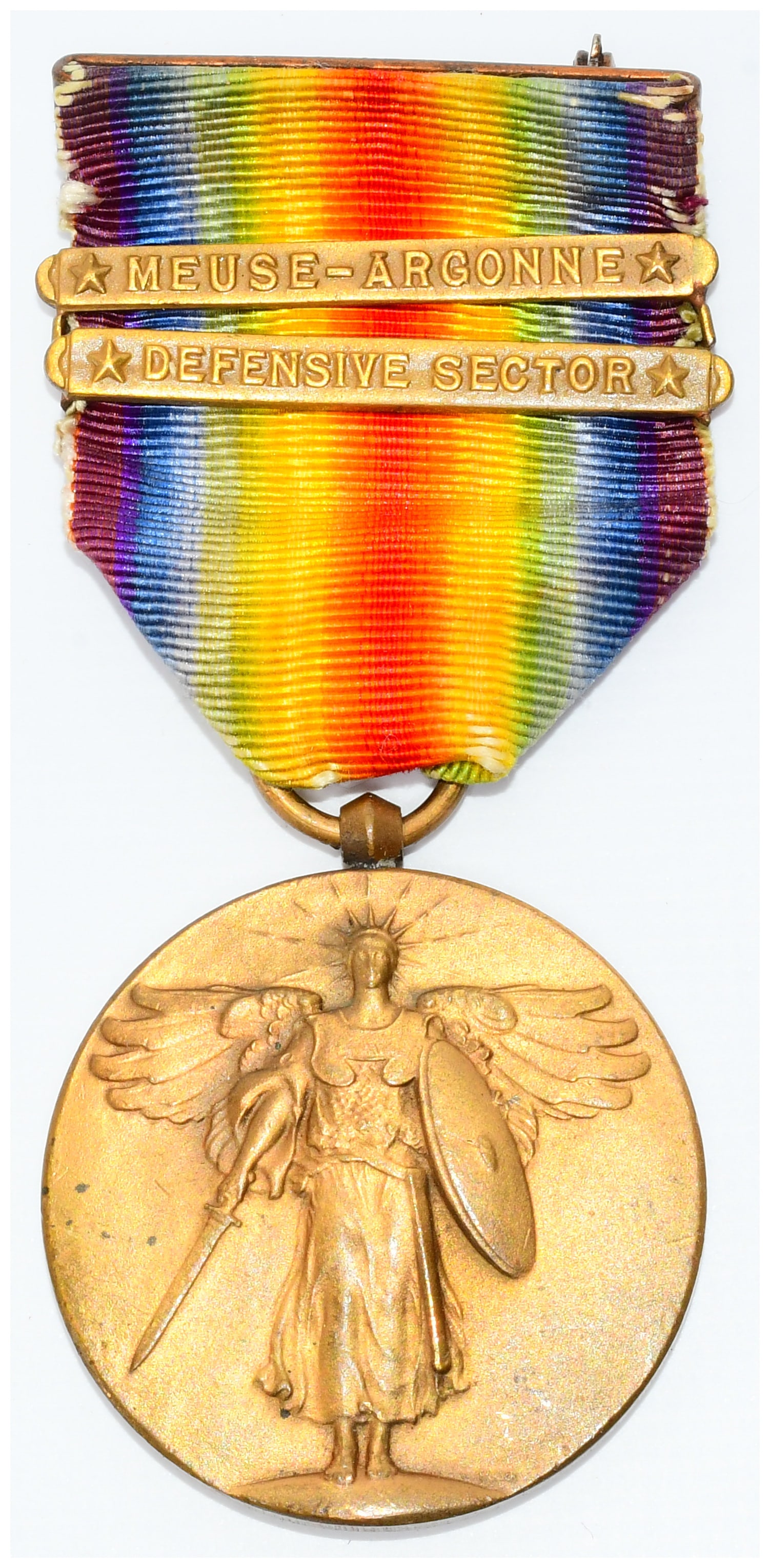 Original U.S. WWI Victory Medal with Meuse-Argonne and Defensive Sector Bars: An original U.S. WWI Victory Medal, featuring a bronze-toned metal circular medal suspended from a polychrome rainbow-striped fabric ribbon, topped with a metal brooch-style pin. The obverse of the me