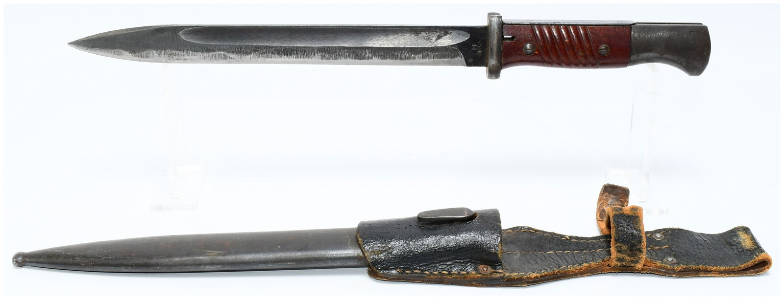 German WWII K98 Mauser Bayonet with Scabbard and Frog, Dated '44': A German WWII K98 Mauser Bayonet, complete with its accompanying metal scabbard and black leather frog. The bayonet features a sharpened, single-edged metal blade with a fuller. The grip is dark reddi
