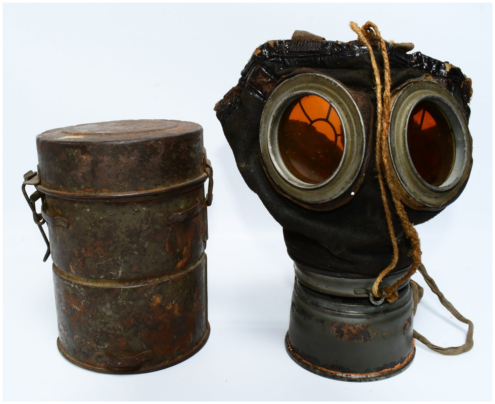 Imperial German WWI M1917 Ledermaske Gas Mask with Can: An Imperial German WWI M1917 Ledermaske Gas Mask with its original carrying canister. The mask features a dark, heavily deteriorated facepiece, appearing to be made of cracked and hardened leather or 