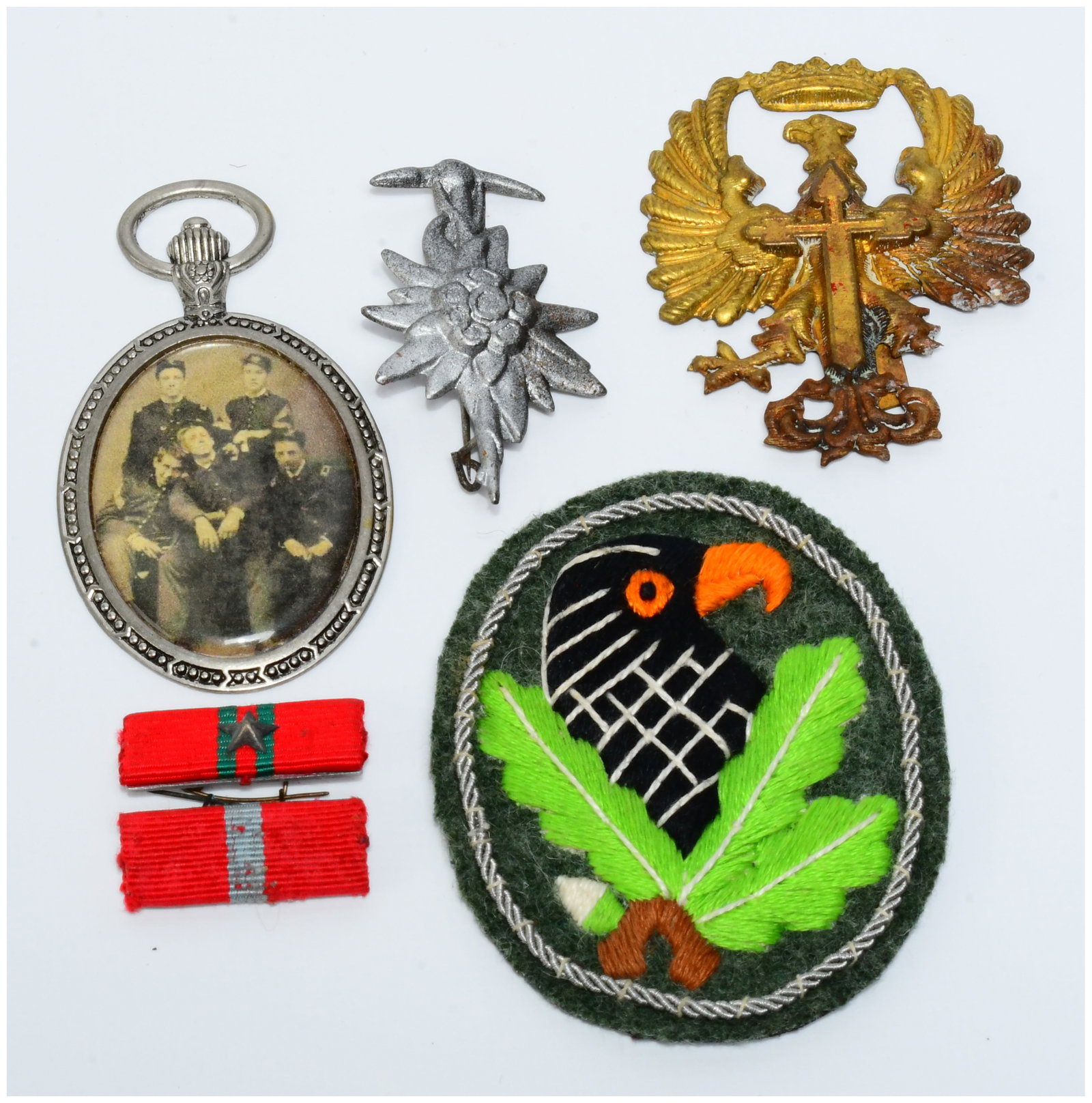 A Collection of German Militaria, including a Second Class Sniper Badge: A collection of German militaria, featuring a circular embroidered Second Class Sniper Badge (Scharfsch?tzenabzeichen) with a black eagle head, orange beak and eye, surrounded by green oak leaves on a