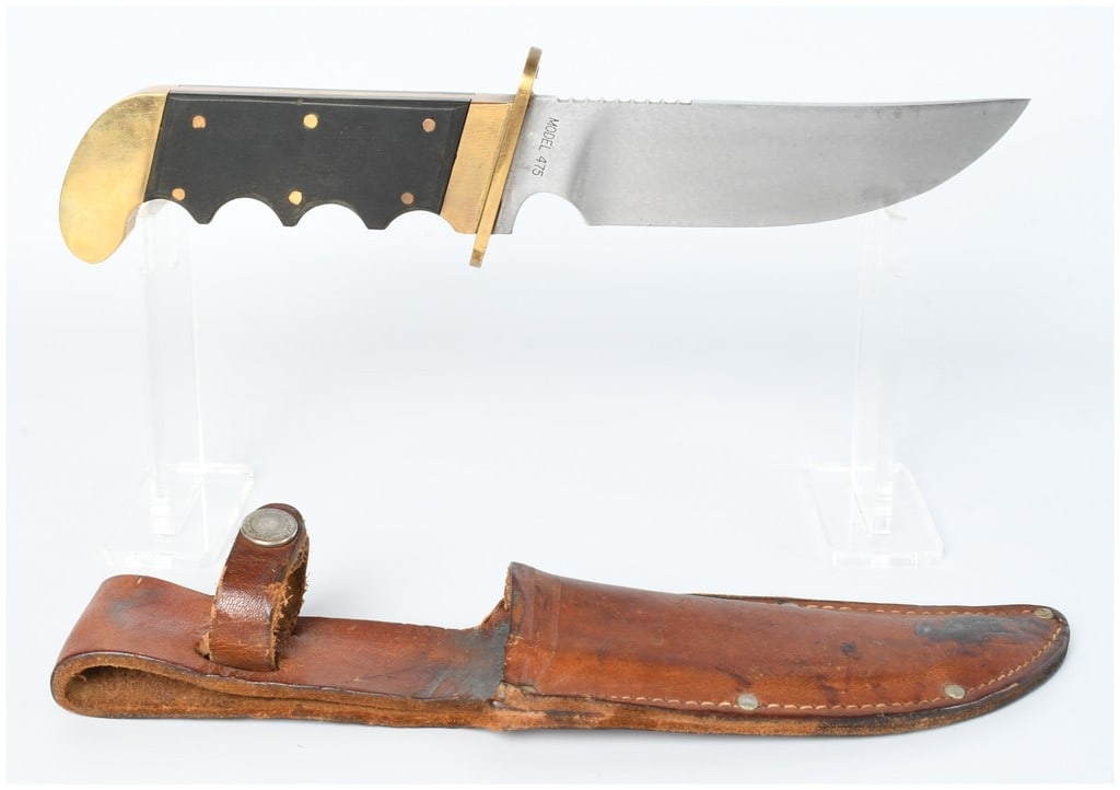 Gerber Model 475 Fixed-Blade Bowie Knife with Sheath: A Gerber Model 475 fixed-blade hunting knife with its accompanying leather sheath. The knife features a satin-finish, drop-point blade, likely stainless steel, with a serrated spine segment near the g