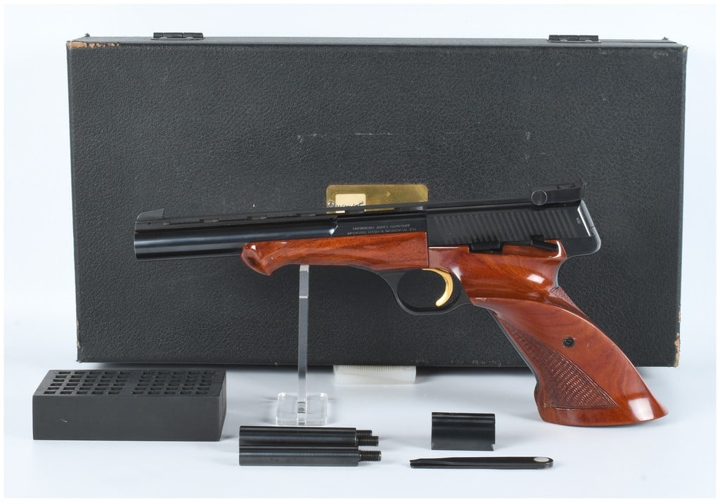 Browning Medalist .22 LR Semi-Automatic Target Pistol with Case and Accessories: A Browning Medalist .22 LR semi-automatic target pistol, featuring a blued metal finish on the frame and barrel. It is fitted with highly polished, reddish-brown wooden ergonomic grips and a gold-colo