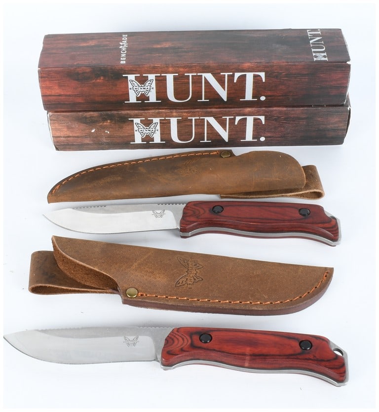 A Pair of Benchmade Fixed Blade Hunting Knives with Sheaths and Boxes: A pair of Benchmade fixed blade hunting knives, each presented with its corresponding leather sheath and original cardboard box. The knives feature drop-point style stainless steel blades with