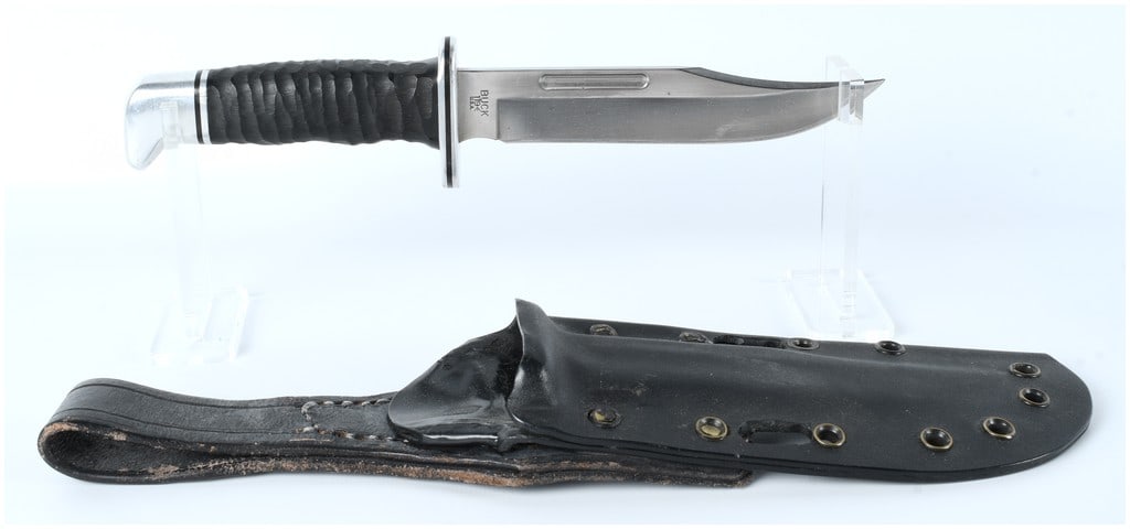 Buck Model 119 Fixed Blade Utility Knife with Sheath: A single lot consisting of a Buck Model 119 fixed-blade utility knife and its associated sheath. The knife features a polished stainless steel clip-point blade with a prominent fuller groove. The hand
