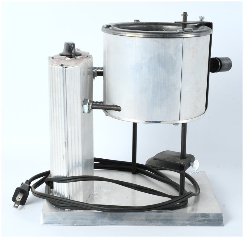 Lee Precision Pro 4-20 Electric Lead Melting Pot Furnace: A single Lee Precision Pro 4-20 electric lead melting pot or furnace, constructed of brushed aluminum sheeting and steel components mounted on a flat metal base. This apparatus is designed for bullet
