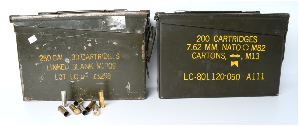 A Collection of Two US Military Surplus Ammunition Cans and Spent Cartridge Casings: A lot comprising two US military surplus metal ammunition cans and a collection of spent cartridge cases. The can on the left is stenciled 250 CAL. 30 CARTRIDGE S LINKED BLANK M1909, with Lot number L