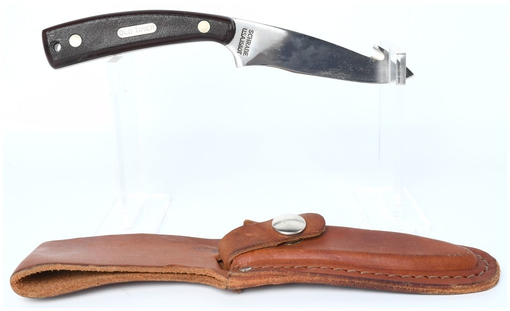 Schrade USA JS80T Old Timer Fixed Blade Hunting Knife and Sheath: This lot consists of one Schrade fixed-blade hunting or utility knife and its accompanying fitted leather sheath. The knife features a stainless steel blade designed with a dropped point and an integr