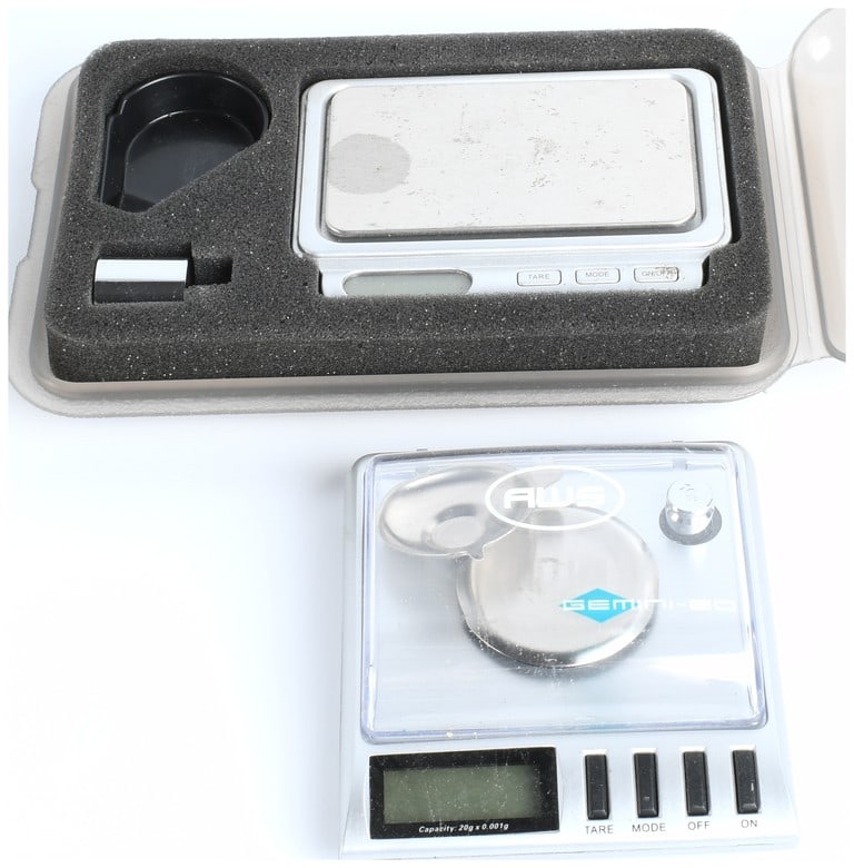 A Collection of 2 Digital Pocket Scales and Accessories: A collection of two portable electronic digital precision scales and three related accessories, including calibration weights and a scoop/tray. Both scales feature silver-toned plastic housing, chrome
