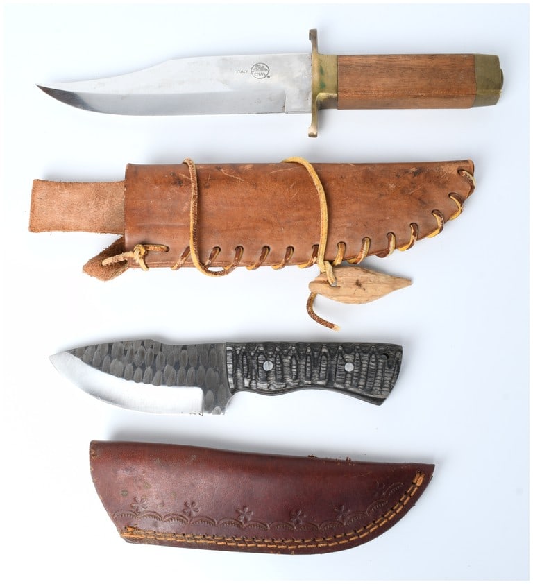A Pair of Fixed Blade Knives including a CVA DIK Italian Bowie Knife and a Forged Drop-Point Hunter: This lot consists of two fixed-blade knives, each accompanied by its leather sheath. The first is a large Bowie-style knife featuring a bright stainless steel clip point blade. The blade is clearly st