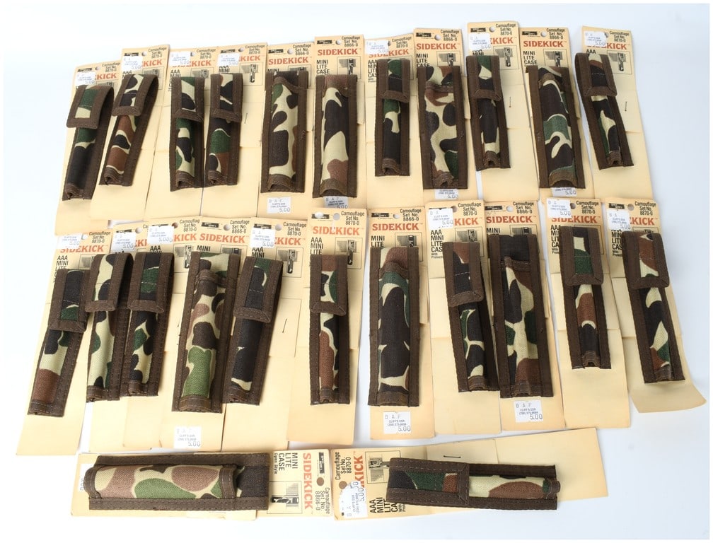 A Collection of 26 Uncle Mike's Sidekick Camouflage AAA Mini Lite Cases: A substantial collection of 26 packaged vintage flashlight accessories identified as Uncle Mike's Sidekick Camouflage Mini Lite Cases. These items are designed to hold AAA Mini Lite flashlights. Each