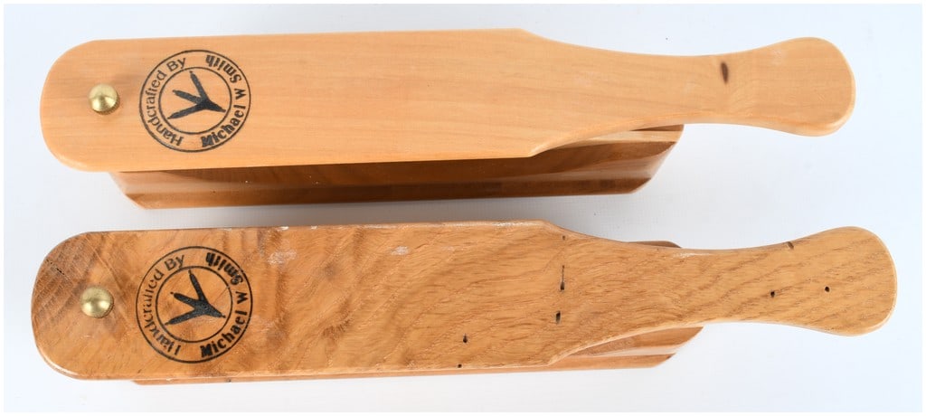 Michael W Smith Handcrafted Pair of Wooden Turkey Box Calls Artisan Stamped: A lot of two matching handcrafted wooden turkey box calls, signed by the artisan Michael W Smith. Each call consists of a multi-sided box body and a separate paddle/lid tapered into a handle shape. Th