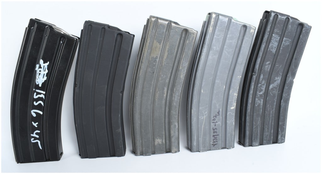 A Group of Five AR-15 30-Round 5.56mm Magazines: A group of five 30-round magazines designed for 5.56x45mm caliber firearms. The collection consists of metal magazines with various finishes including matte black and weathered gray. Manufacturer mark