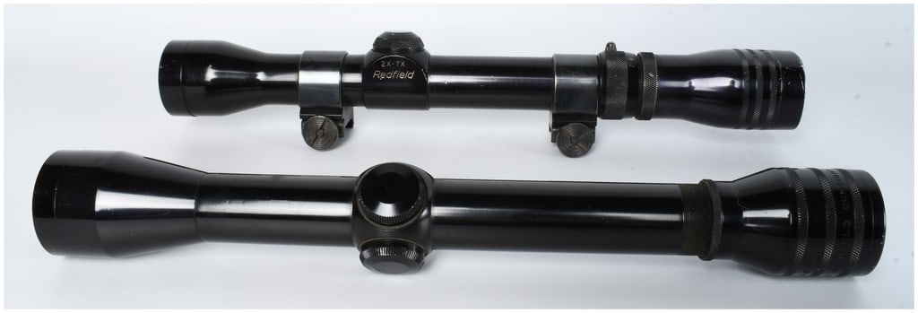Two Redfield Rifle Scopes: Two vintage rifle scopes manufactured by the Redfield Gunsight Co. The first is a 2X-7X variable power model constructed of metal with a black finish. It is marked Redfield on the adjustment turret ho