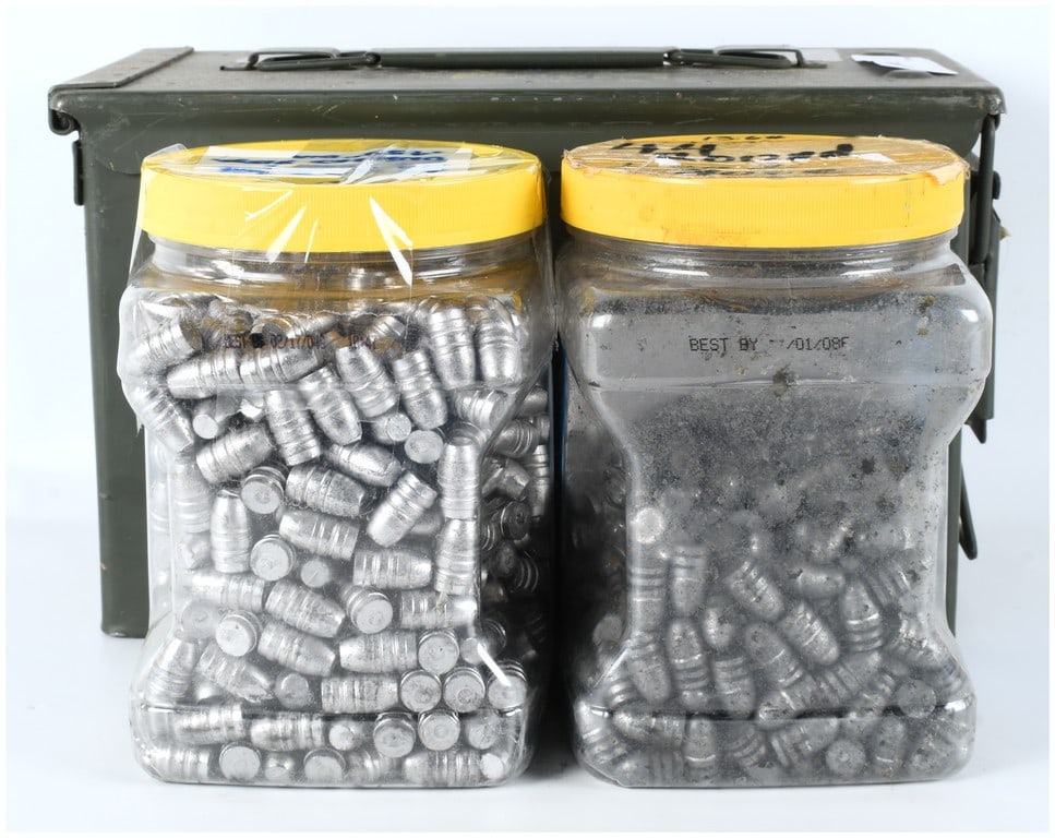 Military Ammunition Can with Two Jars of Cast Lead Reloading Bullets, Circa 2000s: This lot features an olive-drab metal M2A1 style ammunition storage can repurposed to hold two large plastic jars of cast lead projectiles intended for reloading. The metal can is stenciled in yellow