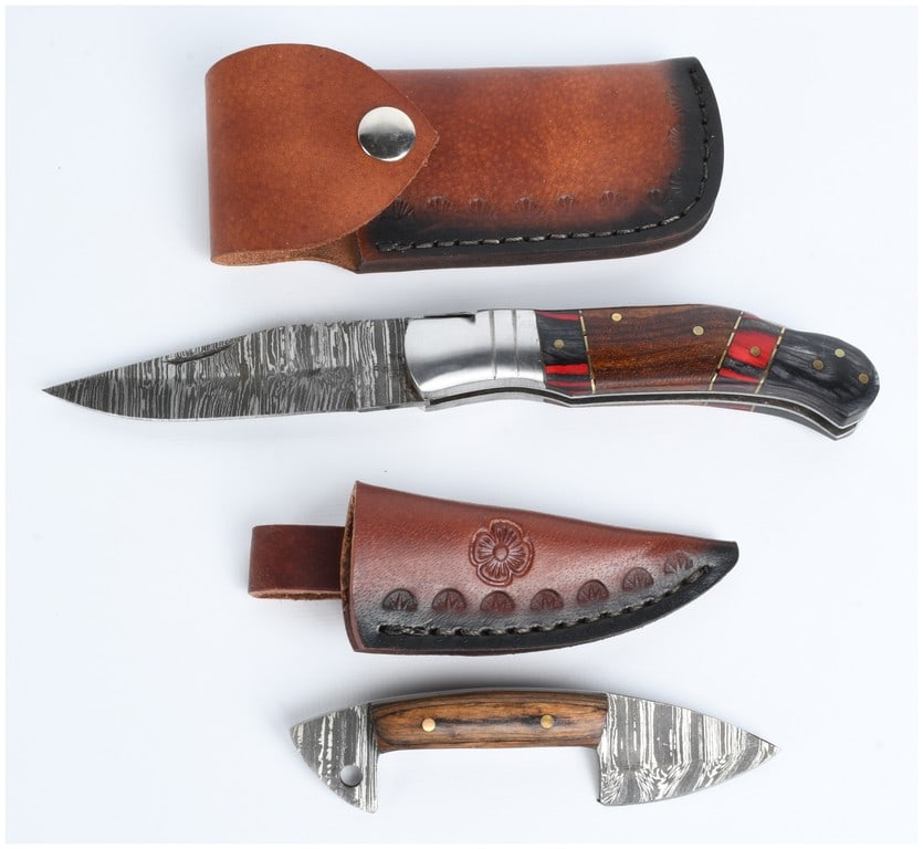 A Pair of Damascus Steel Knives with Leather Sheaths: A collection of 2 contemporary knives featuring Damascus steel blades and coordinating leather sheaths. The first item is a folding pocket knife with a blade showing characteristic wavy steel