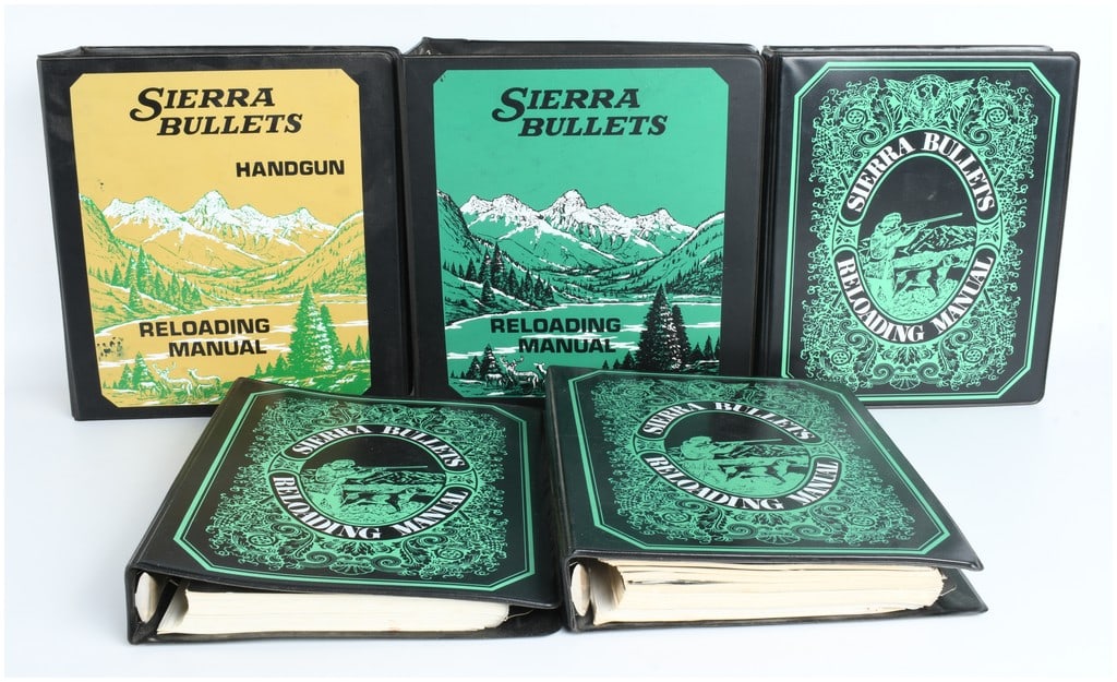 A Collection of Sierra Bullets Reloading Manuals Including Second Edition and Handgun Volumes: A collection of vintage Sierra Bullets reloading manuals housed in three-ring binders. The group features a specialized Handgun Reloading Manual with a yellow mountain landscape graphic and several