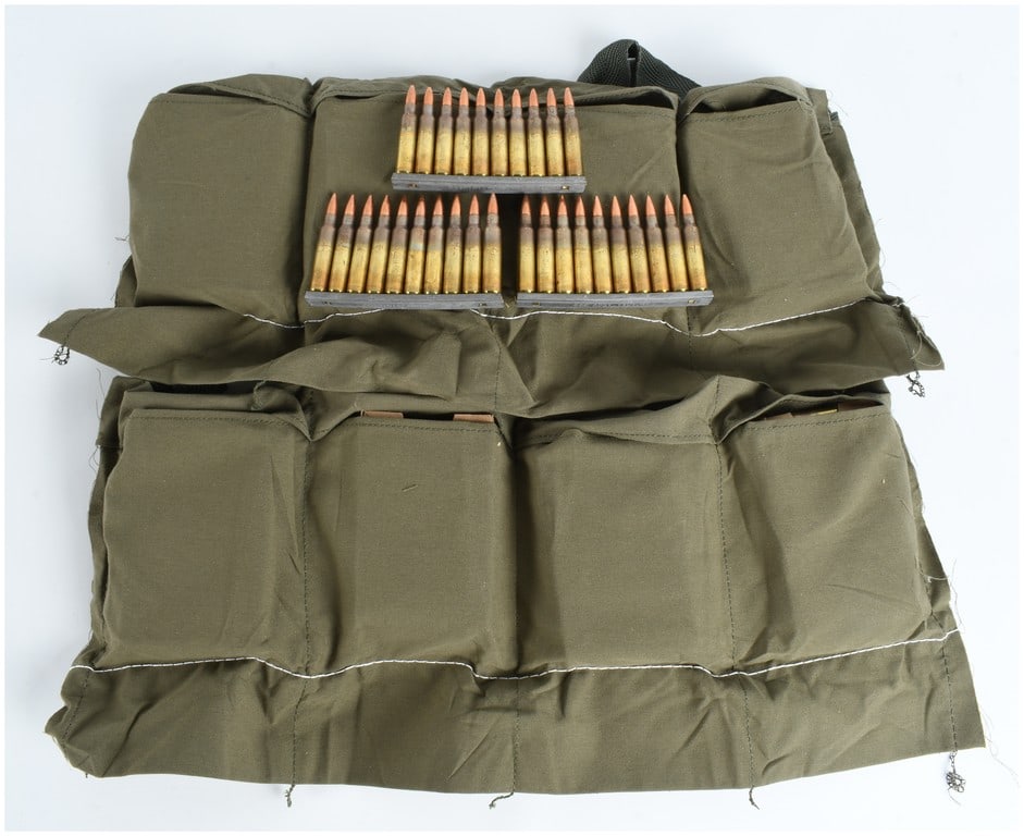 240 Rounds of 5.56mm Ammunition on Stripper Clips with Bandolier: A lot comprising 240 rounds of 5.56x45mm NATO ammunition, secured to 10-round metal stripper clips and presented with an Olive Drab (OD) green cotton canvas bandolier. The ammunition is identified as 