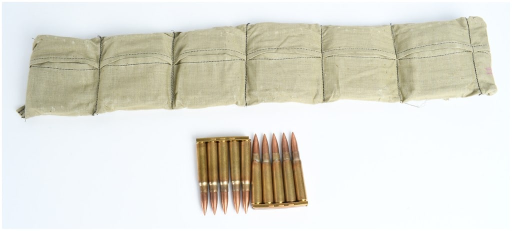 A Lot of 70 Rounds of 8mm Mauser Ammunition on Stripper Clips: This lot consists of 70 rounds of 8mm Mauser centerfire rifle ammunition organized onto five-round stripper clips and housed within a six-pocket khaki canvas bandolier. The cartridges feature brass ca