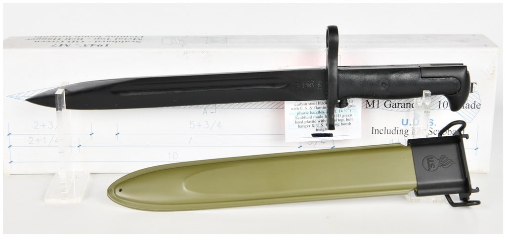 Brand New Reproduction U.S. Military M1 Garand 10-Inch Bayonet with M7 Scabbard: A brand new contemporary reproduction of a United States military M1 bayonet for the M1 Garand rifle, presented in its original retail packaging. The bayonet features a parkerized carbon steel blade w