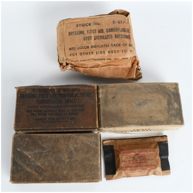 A Collection of World War II United States Military First Aid Dressings and Sulfadiazine Tablets: This collection consists of six pieces of United States military medical equipment dating to the World War II era. The assortment includes a Carlisle Model first aid packet featuring an olive drab tre