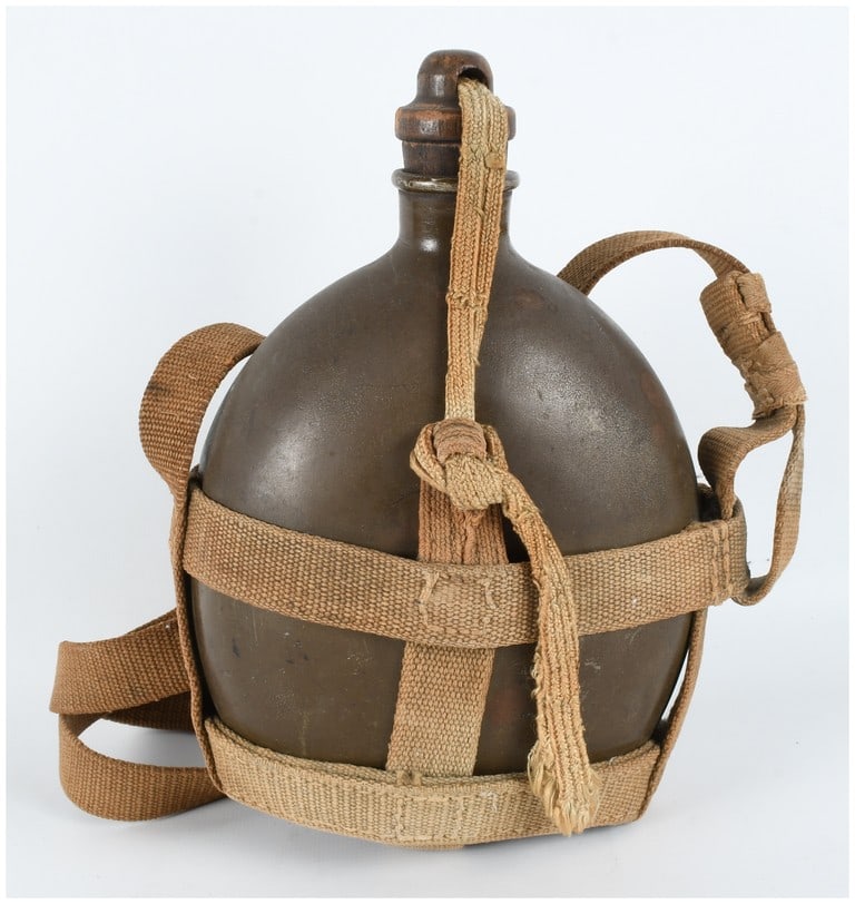 WWII Imperial Japanese Army Type 99 Aluminum Canteen with Webbing Harness: A standard-issue Imperial Japanese Army Type 99 water canteen dating to the World War II era. The canteen features a rounded aluminum body finished in its original khaki/brown paint. It is fitted with
