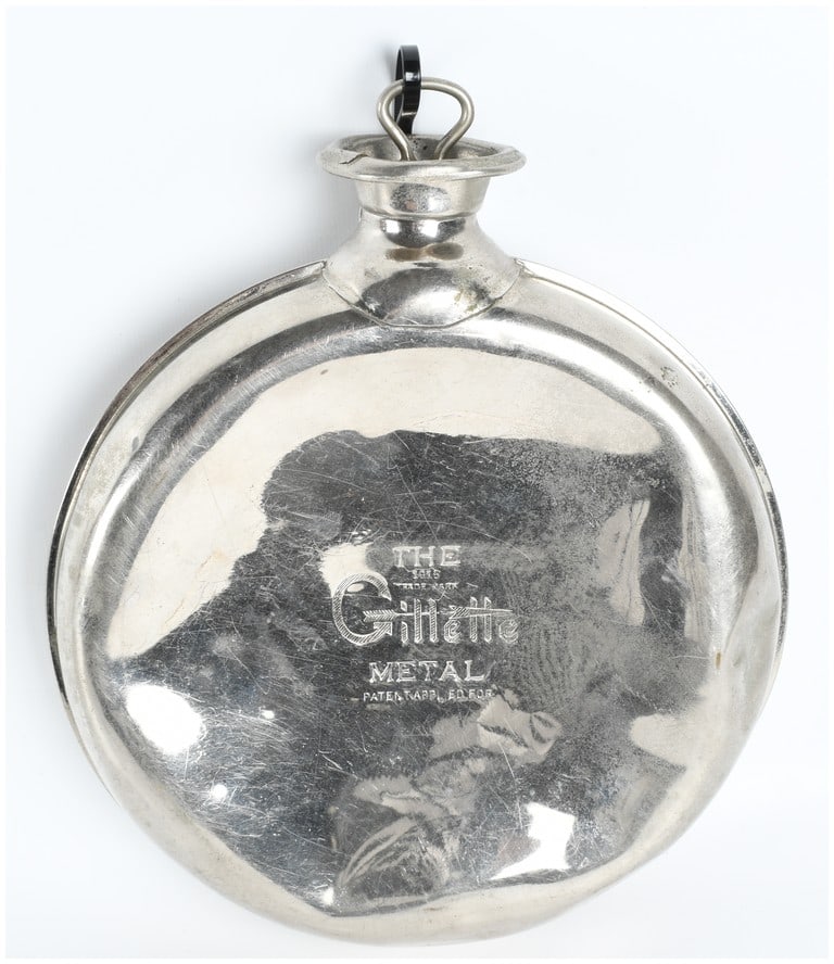 Antique Gillette 1915 Metal Hot Water Bottle: An antique circular metal hot water bottle produced by the Gillette Safety Razor Co. This single item is constructed from a silver-toned metal, likely nickel-plated brass or steel. The piece features 