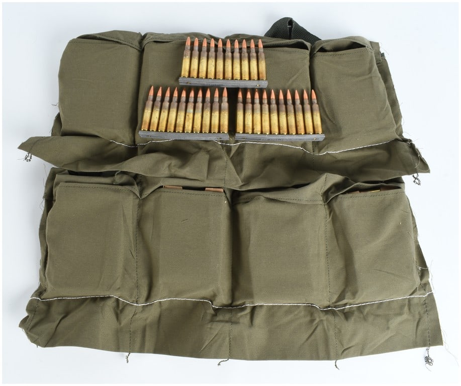 A Lot of 240 Rounds of 5.56x45mm NATO Ammunition on Stripper Clips with Bandoleer: This lot consists of 240 rounds of 5.56x45mm NATO centerfire rifle ammunition, mounted on ten-round metal stripper clips and presented with a canvas bandoleer. The cartridges feature brass cases with 