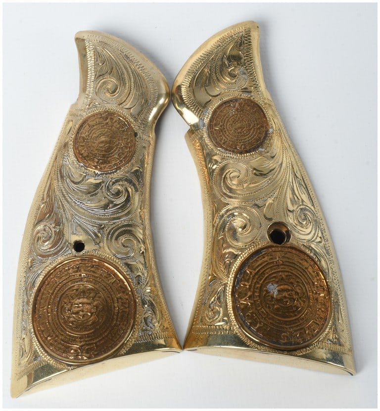 A Pair of Mexican Silver and Gold-Plated S&W K-Frame Square Butt Revolver Grips: A pair of Mexican silver and gold-plated handgun grips specifically designed for a Smith & Wesson K-frame square butt revolver. These mid-20th-century grips are executed in the "Charro" style, featuri