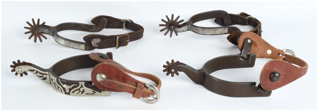 An Assortment of Vintage Western Engraved Steel Spurs with Leather Straps: An assortment of Western-style equestrian spurs featuring dark-finished steel construction and engraved silver-toned overlays. The collection includes spurs decorated with floral scrollwork patterns a