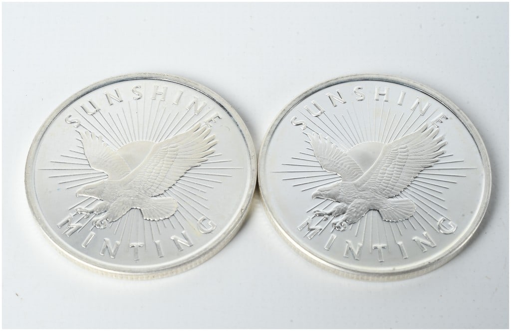 A Pair of Sunshine Minting 1 Troy Ounce .999 Fine Silver Bullion Rounds: This lot consists of two silver bullion rounds manufactured by the private refiner Sunshine Minting. Each round is struck from one troy ounce of .999 fine silver. The obverse of each round features th