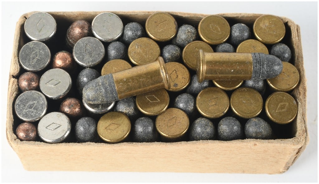 A Lot of 49 Western .22 Short Rimfire Ammunition Rounds: This lot consists of 49 rounds of Western .22 Short rimfire ammunition, including both complete cartridges and spherical projectiles, housed in a worn cardboard tray. The collection features cartridge