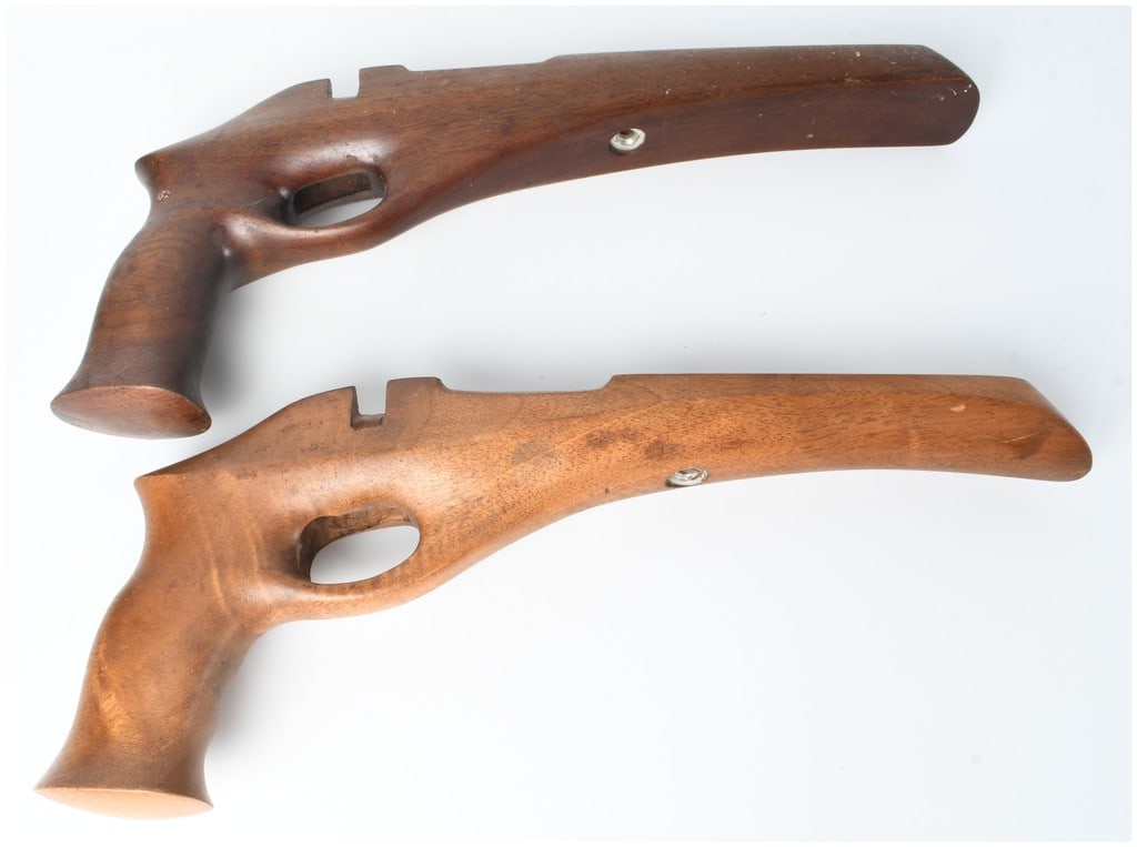 A Pair of Hand-Crafted Wooden Rubber Band Pistols: This lot consists of a pair of hand-crafted wooden rubber band pistols featuring an ergonomic, skeletonized frame design with integrated forends and pistol grips. The top pistol is constructed from a 