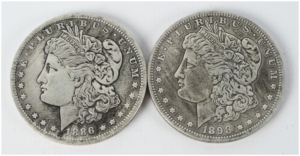 A Pair of US 1886-O and 1893-O Morgan Silver Dollars: This lot contains 2 US Morgan silver dollars minted at the New Orleans facility. The collection includes an 1886-O and an 1893-O issue. Both coins are struck in 90% silver and 10% copper. The coins fe