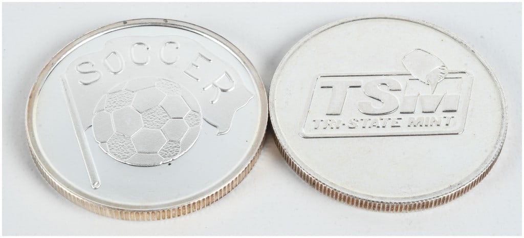 Two 1 oz .999 Fine Silver Rounds including Soccer and Tri-State Mint Designs: This lot consists of two silver bullion rounds, each containing one troy ounce of .999 fine silver. The first round is soccer-themed, featuring an obverse design of a soccer ball and flag with the wor