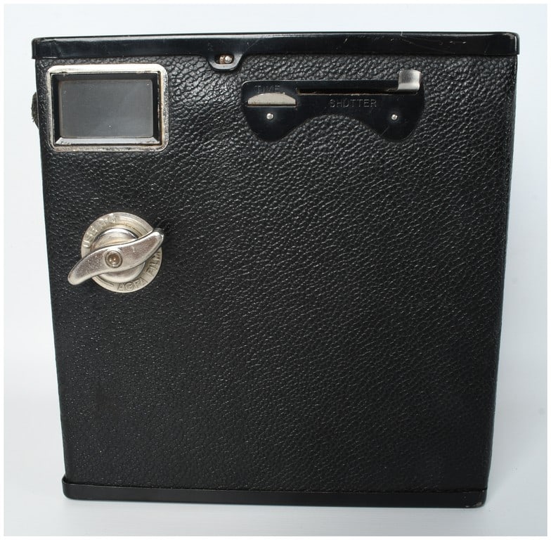 Agfa Ansco D-6 Cadet Box Camera: A vintage Agfa Ansco D-6 Cadet box camera manufactured in Binghamton, New York. The camera features a rigid rectangular body covered in black pebble-grained leatherette. The front face is embossed wit