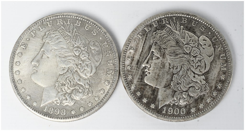 A Pair of US Morgan Silver Dollars, 1898 and 1900: A pair of US Morgan silver dollars struck at the Philadelphia Mint, dated 1898 and 1900. These coins are composed of .900 fine silver. Both specimens exhibit the standard Morgan dollar design type wit