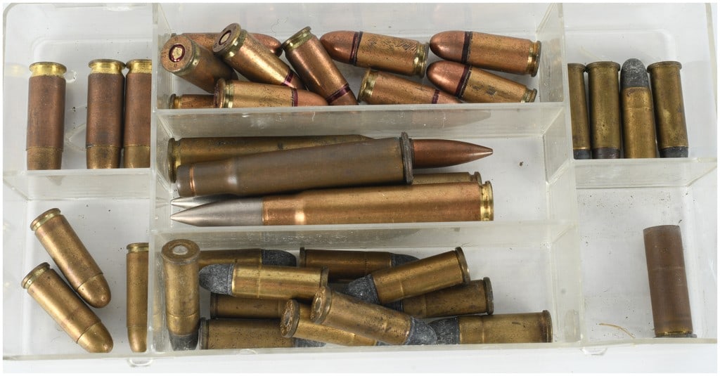 A Lot of 34 Rounds of Mixed Collector Ammunition: This lot consists of 34 rounds of mixed collector ammunition housed within a multi-compartment clear plastic organizer. The collection represents a variety of calibers and manufacturers, including bot