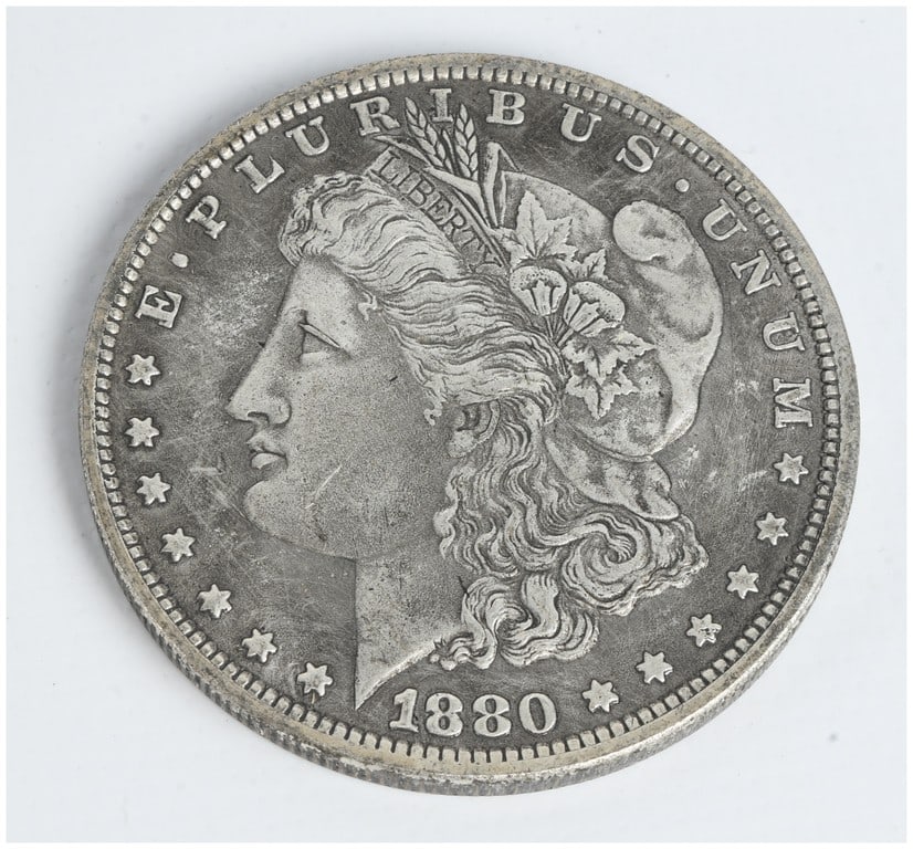 1880-S US Morgan Silver Dollar: One US 1880-S Morgan silver dollar. This coin was struck at the San Francisco Mint and features the S mint mark on the reverse, positioned between the wreath and the denomination. The design, by Georg