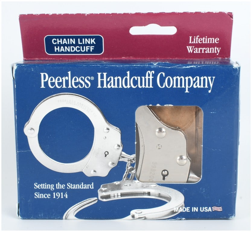 Peerless Handcuff Company Model 700C Chain Link Handcuffs with Original Box: A set of Peerless Handcuff Company chain link handcuffs accompanied by the original retail box. The handcuffs are constructed of nickel-plated steel and feature two rotating bows connected by two-link
